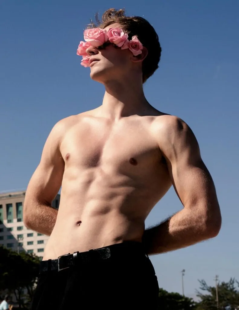 a man posing under the sun flexing his abs