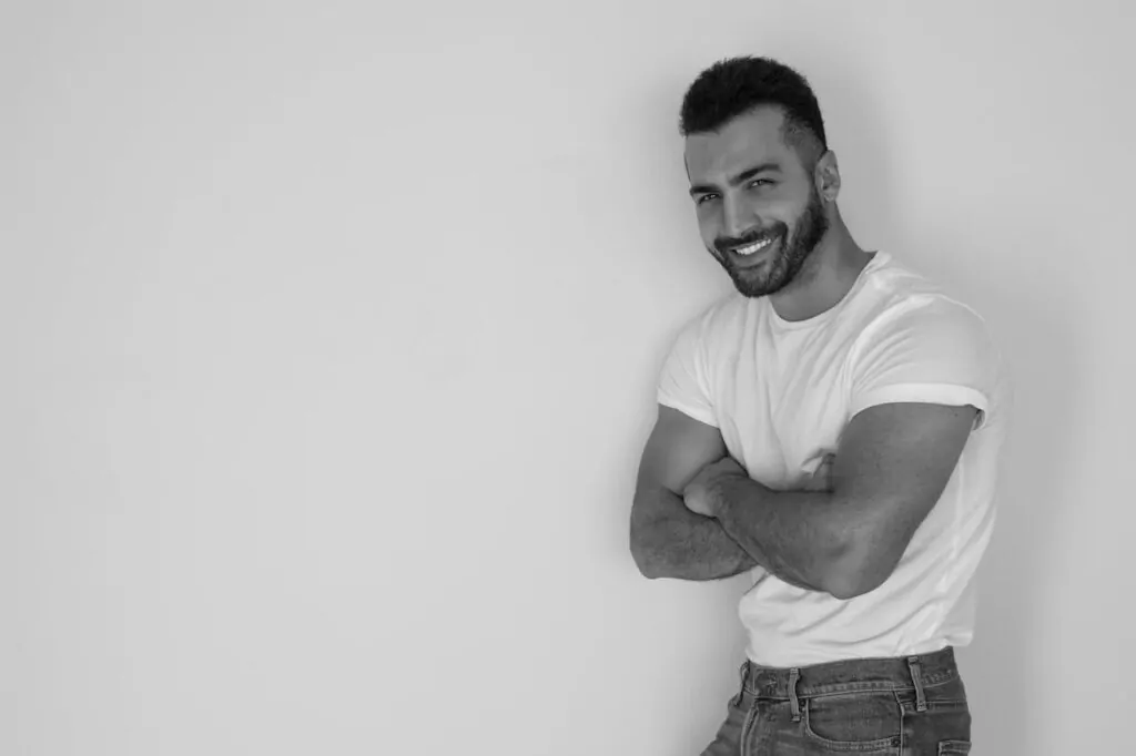 a man posing by a white background after cosmetic surgery