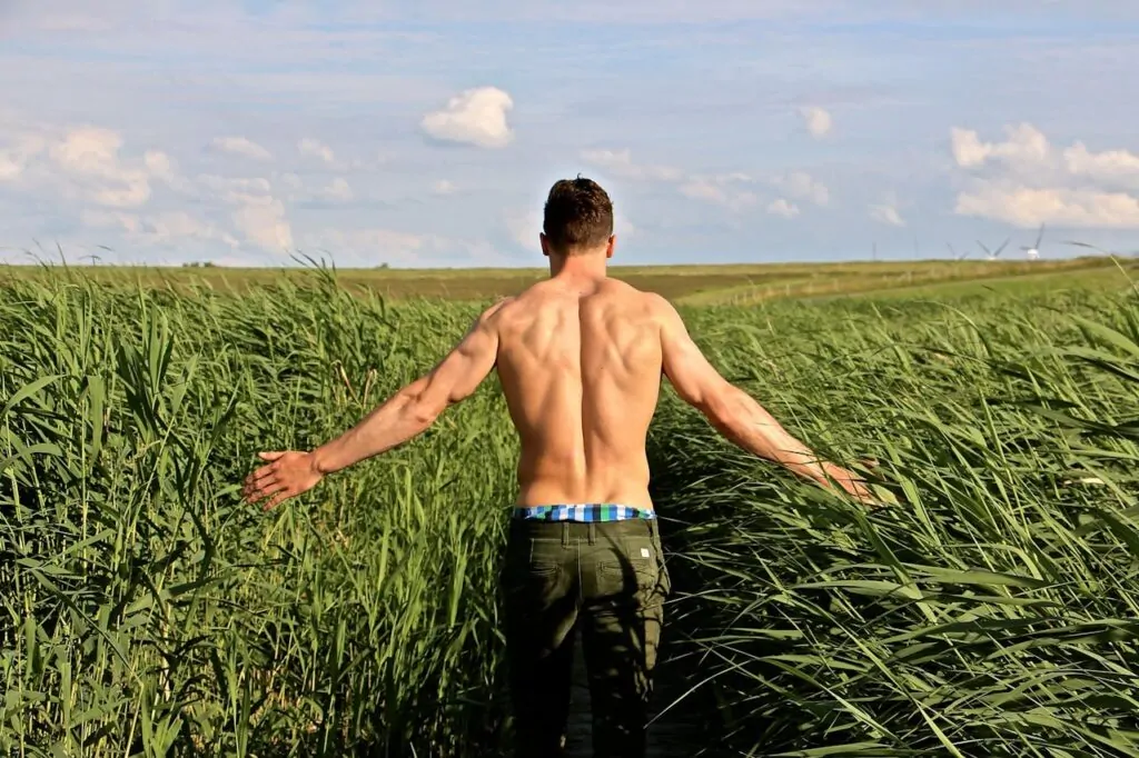 man flexing his back muscles after plastic surgery