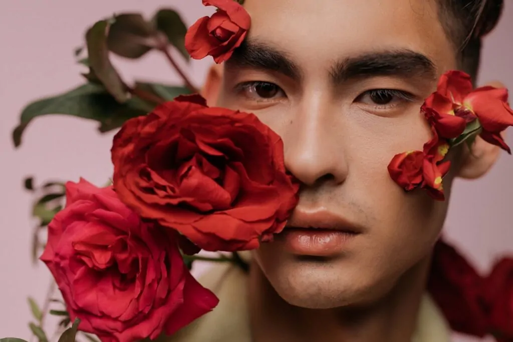 man posing with red roses around his face after facial plastic surgery