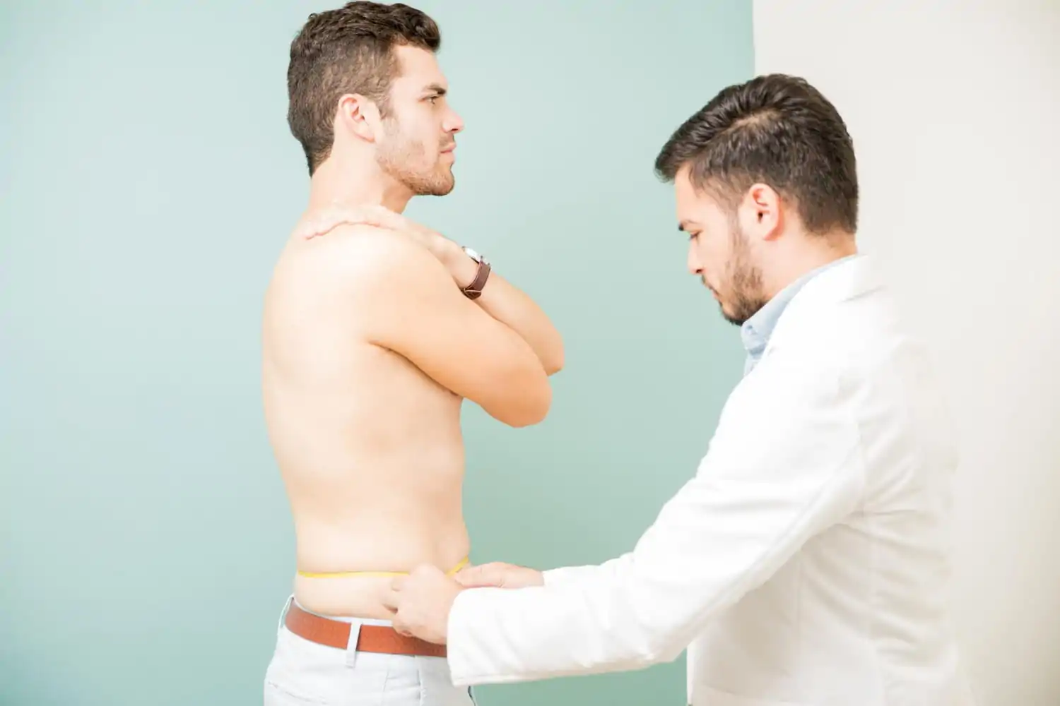Plastic surgeon measuring a patients waist before liposuction procedure