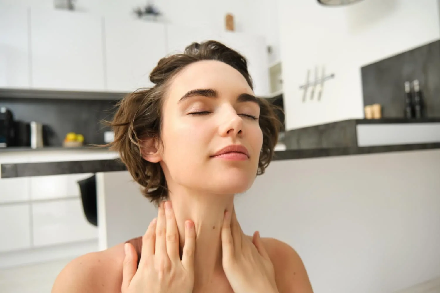 Woman touching firm neck skin demonstrating non-surgical skin tightening results