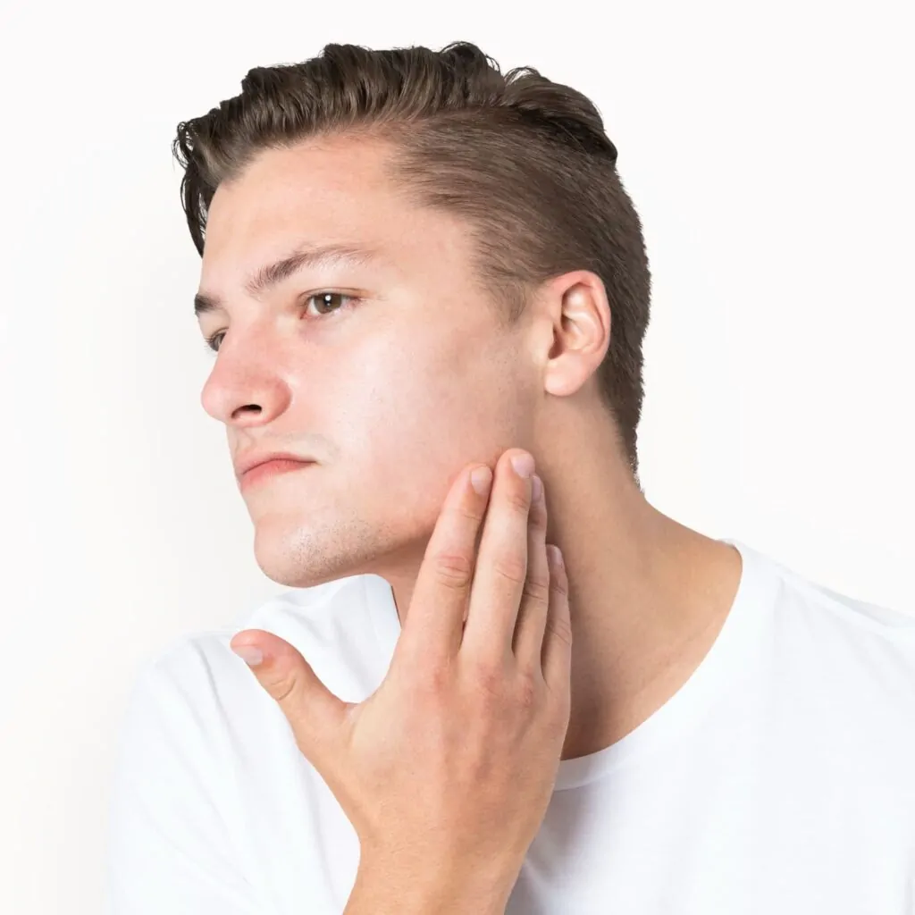 Man examining his jawline and neck area, considering non-invasive skin tightening treatment options