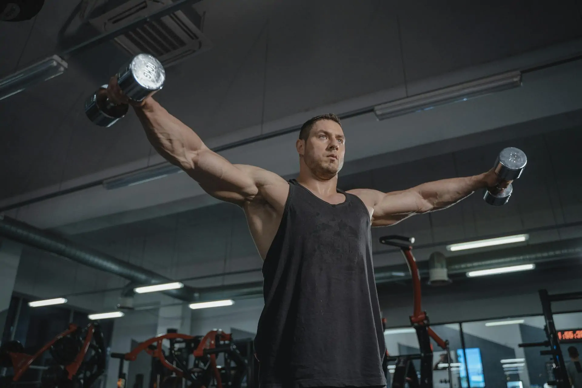 Man flexing his underarms at the gym after liposuction