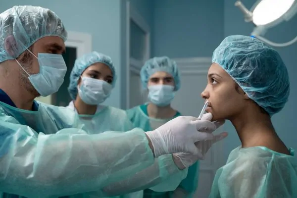 Cosmetic surgeon with equipment checking patient
