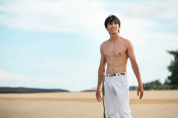 Man by the beach flexing his abdomen after tummy tuck