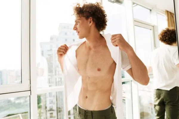 Man getting dressed and showing his liposuction result