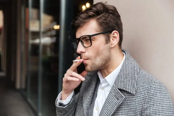 Side view of a smoking man thinking of getting neck liposuction