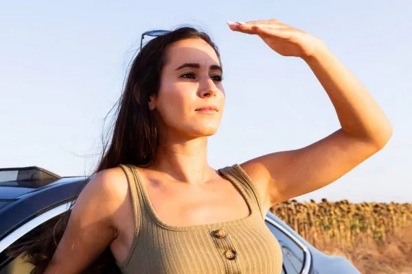 Woman covering her face from sun exposure after plastic surgery
