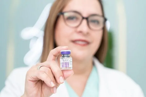 A surgeon holding a bottle of Botox treatment
