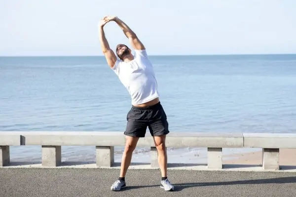 Muscular man doing side bend exercise outdoors