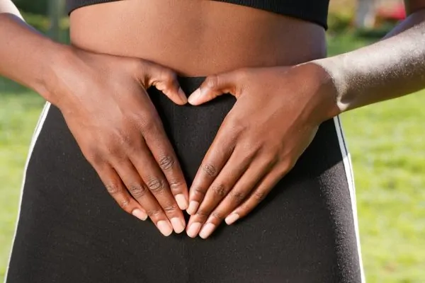 A woman touching her belly after pregnancy and a mommy makeover