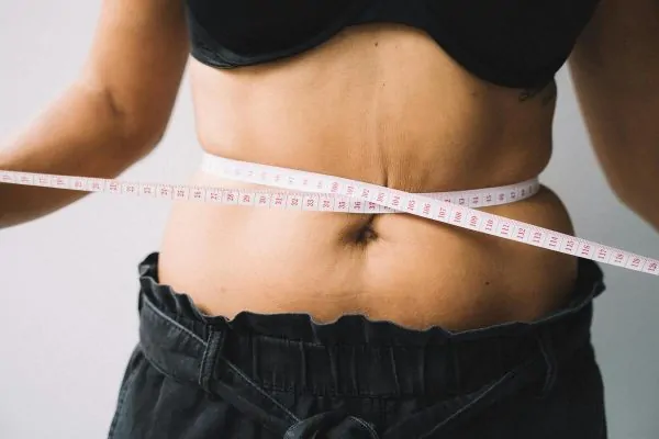 A woman measuring her tummy with a tape measure