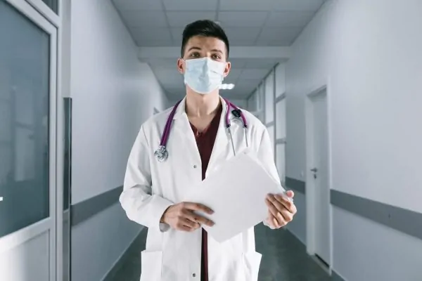 Doctor wearing a mask and holding a peptide prescription