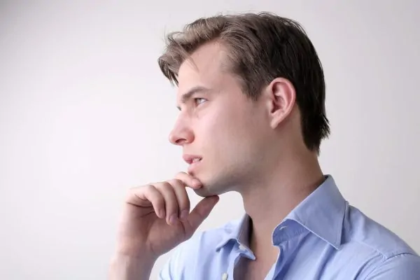Man touching his chin after getting a chin reduction procedure