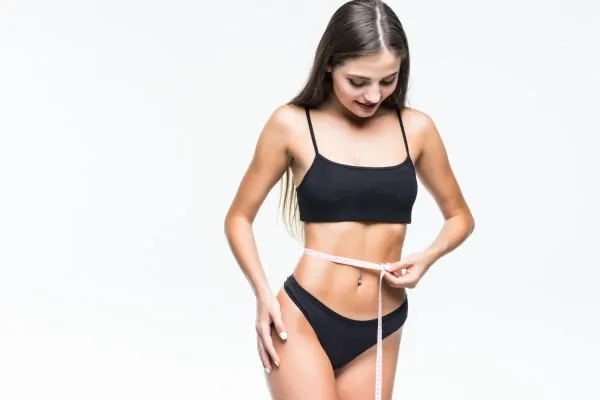 Woman measuring her waist after plastic surgery and peptide therapy