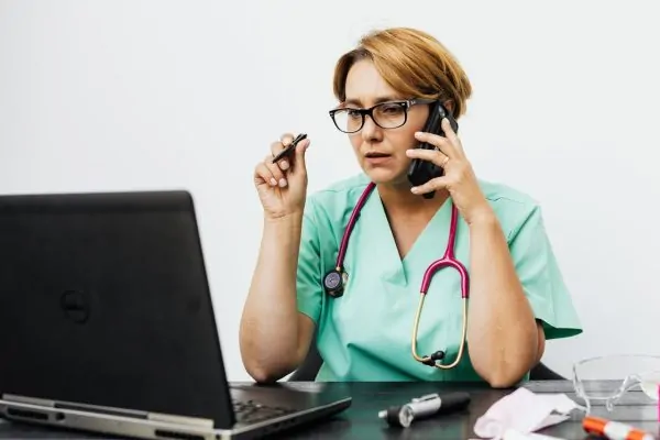 A plastic surgeon talking to the phone with a patient