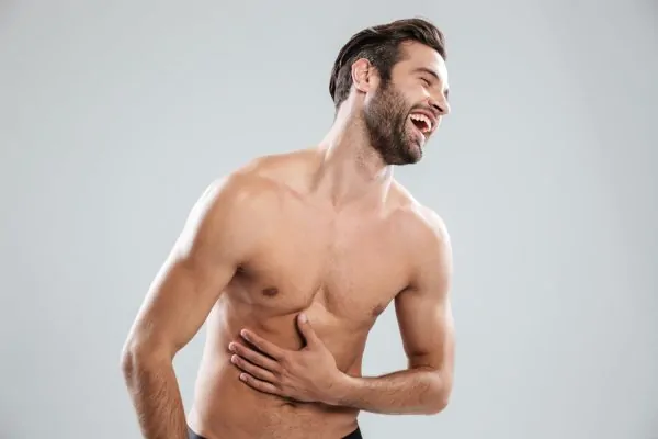 Man laughing and touching his sculpted body after getting HD liposuction