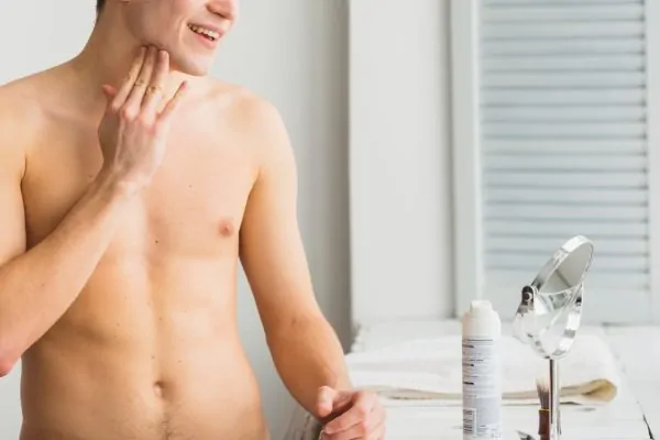 Man standing in front of the mirror touching his neck after getting neck liposuction