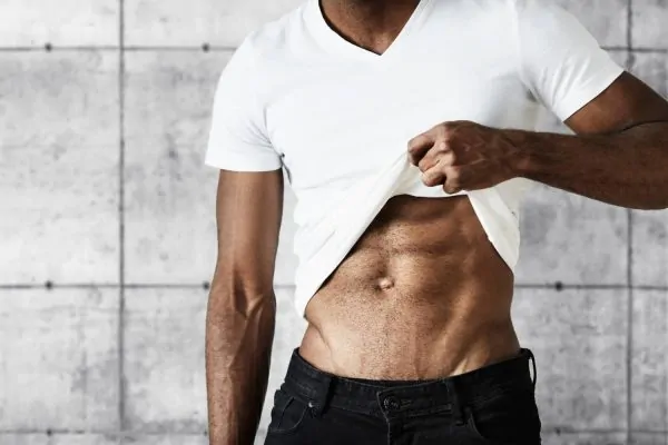 Man wearing white shirt showing his liposuction results