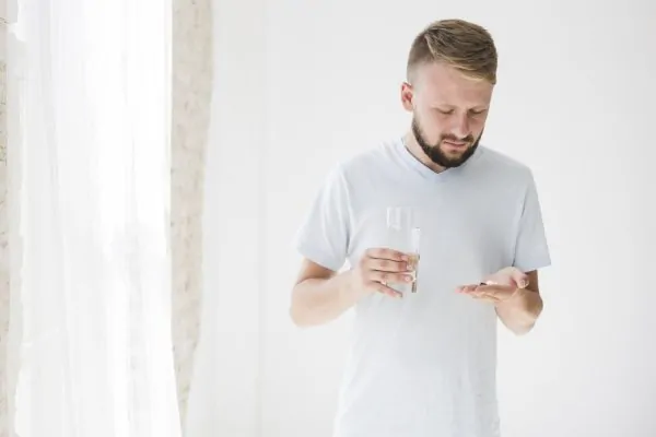 A man with medication and water for his liposuction recovery.