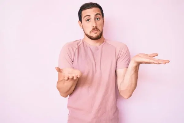 A confused man shrugging both hands, questioning how common reconstructive surgery is among patients