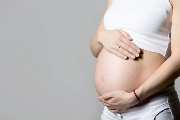 A pregnant woman gently cradling her baby bump, representing the important safety considerations around getting Botox during pregnancy.