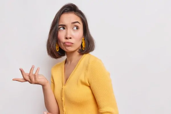 A puzzled young woman raising her hand with a questioning expression, wondering how Botox actually works and what happens during the treatment process