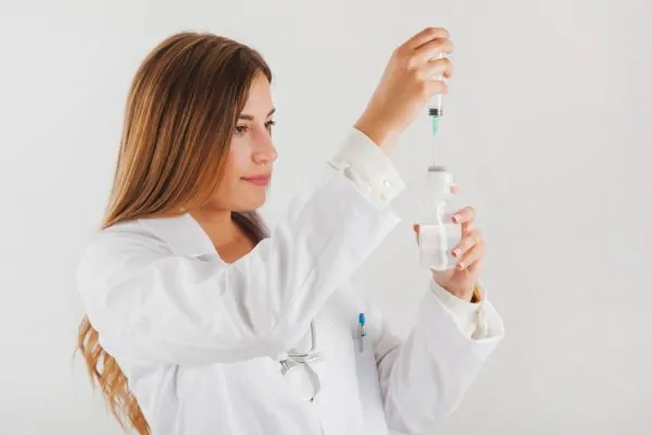 A skincare professional in a white lab coat carefully drawing a peptide solution from a vial with a syringe, highlighting the science behind understanding peptides in your skincare routine.
