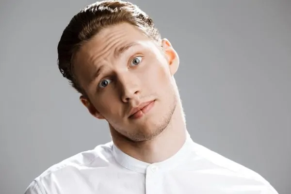 A young man raising one eyebrow with forehead lines, curiously questioning why Botox is used as a cosmetic treatment