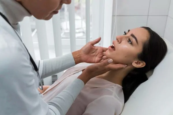Doctor examining patient's jawline to assess filler placement and longevity