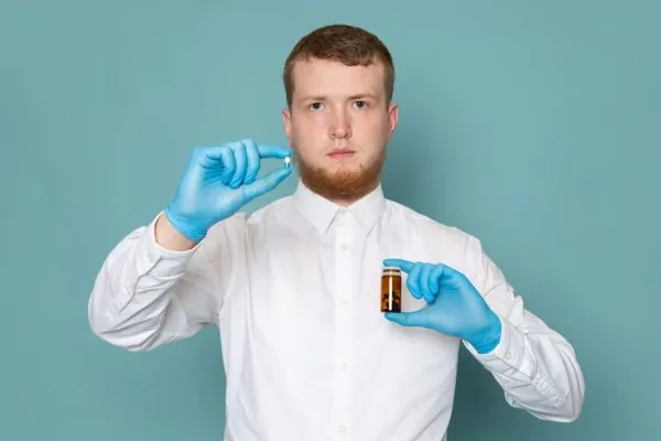 Healthcare professional in blue gloves holding medication vial and syringe, demonstrating tesamorelin acetate injection preparation