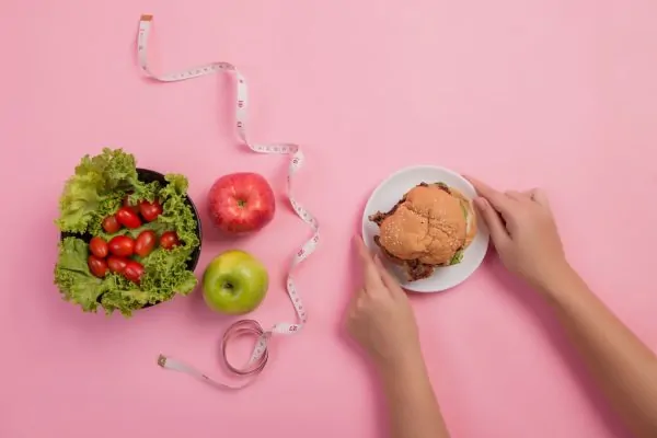 Healthy food choices versus processed burger showing optimal nutrition for liposuction recovery and results