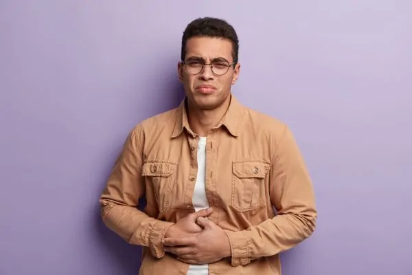 Man holding his abdomen in discomfort, illustrating hernia symptoms and development factors