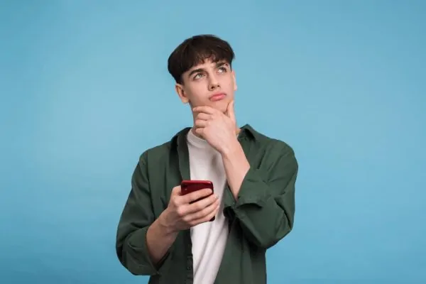 Man looking thoughtful while researching what high-definition liposuction is on his phone