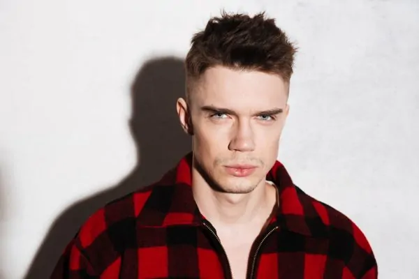 Man with prominent cheekbones and defined facial contours in plaid jacket, exemplifying amplified masculine characteristics achievable with PDO thread lift