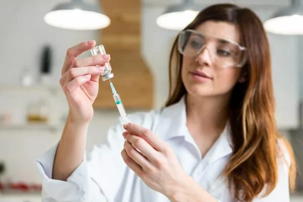Medical practitioner examining peptide medication vial before administration in clinical setting