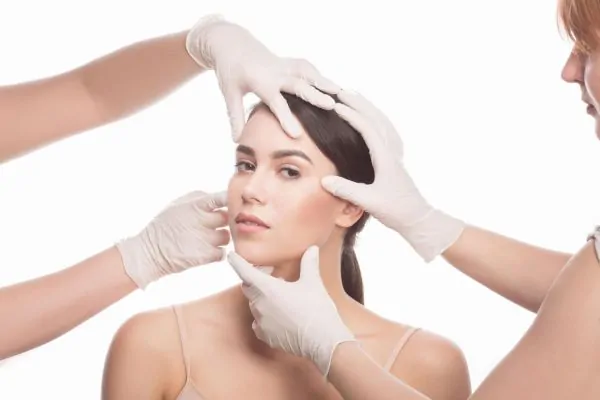 Multiple gloved hands examining woman's face for cosmetic thread lift consultation and assessment