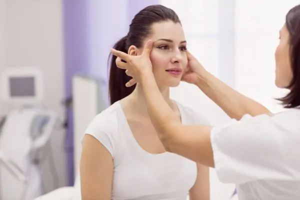Patient receiving facial assessment from cosmetic specialist to understand PDO thread lift procedure