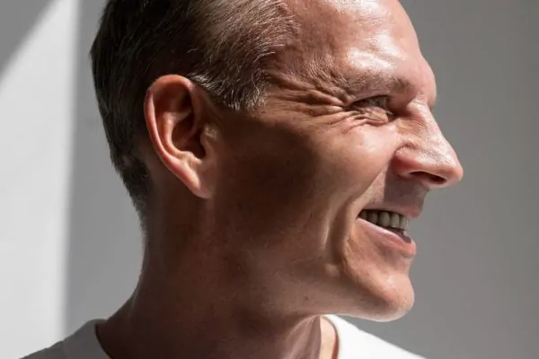 Side profile of a smiling man with a smooth defined jawline and neck after turkey neck surgery