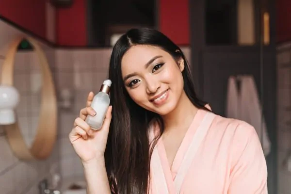 Smiling woman holding peptide skincare product as part of daily beauty regimen
