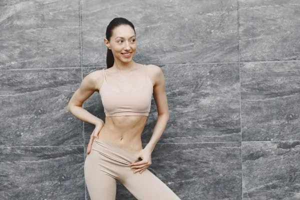 Smiling woman wearing beige compression garment for post-liposuction recovery and body contouring support