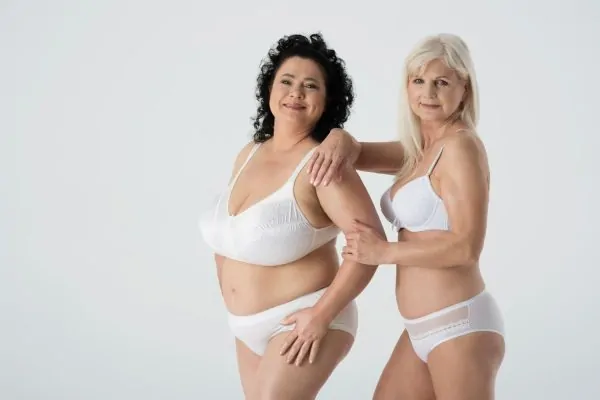Two women over 50 in white undergarments displaying different body types, demonstrating tummy tuck candidacy across ages and sizes
