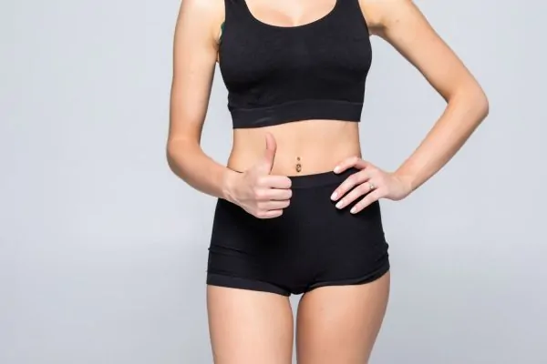 Woman displaying flat abdomen after successful tummy tuck recovery with minimal swelling results