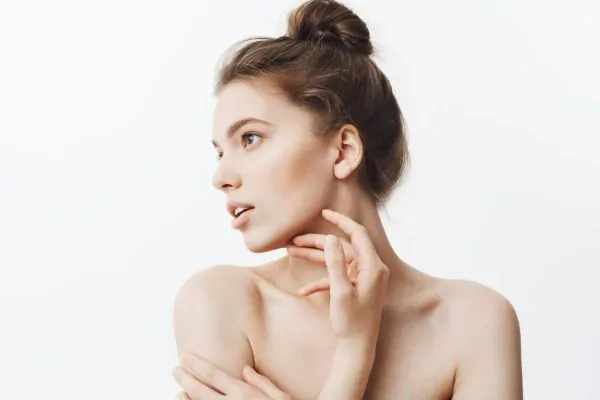 Woman examining her jawline and neck area, checking for concerns that may require medical consultation after non-surgical facelift
