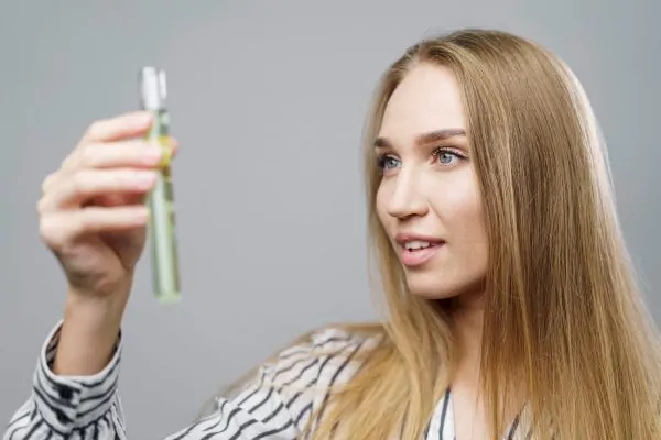 Woman examining peptide serum vial, demonstrating understanding of peptides for skin and hair care