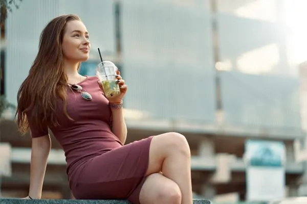 Woman relaxing outdoors with beverage, illustrating healthy lifestyle choices during post-liposuction recovery period