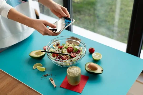 Woman tracking healthy meal with app showing nutritious salad and avocado for post-liposuction wellness