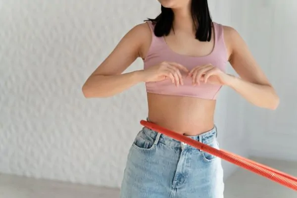 Woman using hula hoop showing flat midsection representing potential benefits of tummy tuck surgery