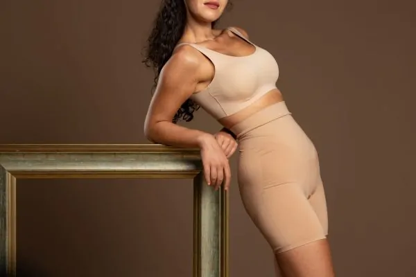 Woman wearing beige medical-grade compression garment for post-surgical recovery after body contouring
